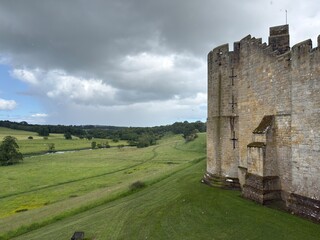 Medieval Defense: Ancient yellow stone castle walls overlooking lush green countryside © Curiosity Photos