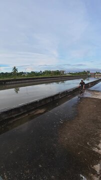 Man Riding Bicycle on Waterlogged Path