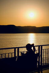 Fototapeta premium Silhouette of woman on boat at sunset