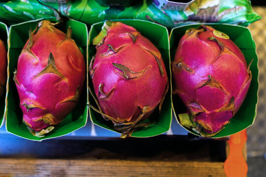 Fresh dragon fruit displayed in green packaging at a market in France for sale
