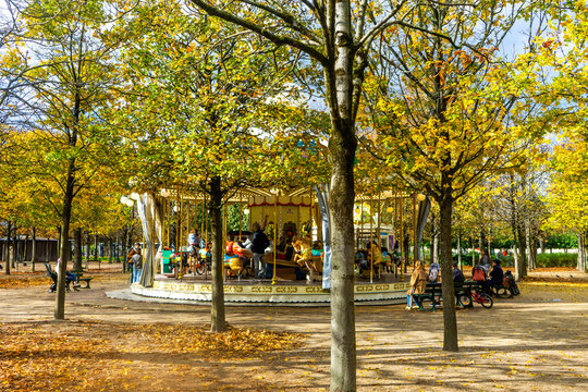Merry-go-round spins in Tuileries as leaves fall in autumn on a sunny day in Paris, France