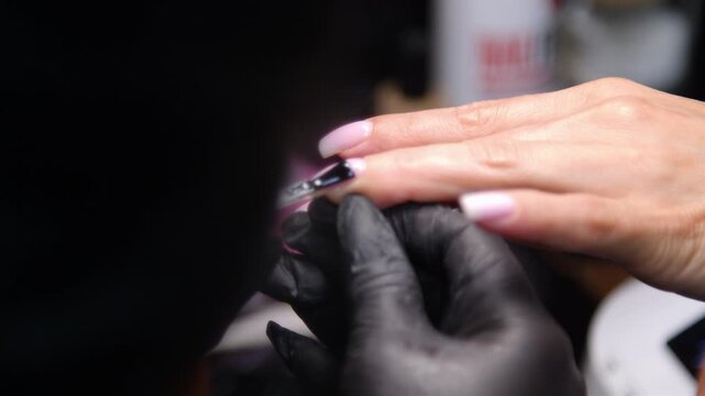 A woman's hand during a manicure. A woman getting a manicure. A manicurist is doing a client's nails at a nail salon. Beauty salon concept: manicures, pedicures.