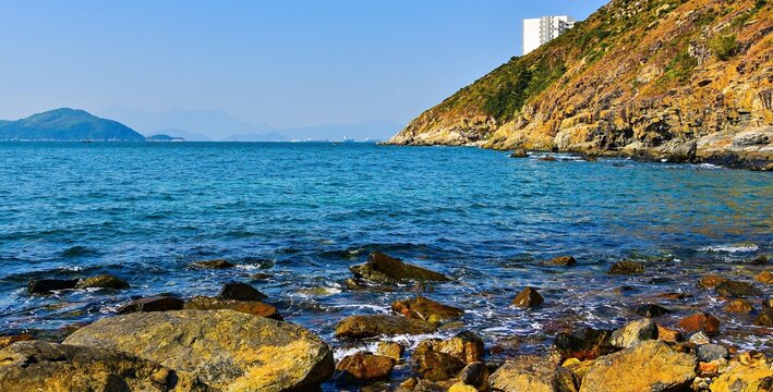 Rocks and hill at sea near Mount Johnston in Ap Lei Chau, Hong Kong capture the coastal landscape and clear blue waters