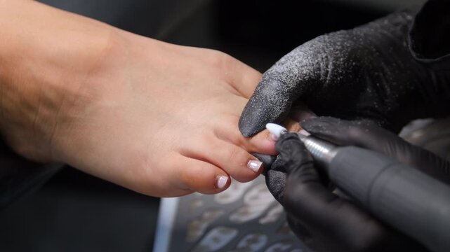 A woman's feet during a pedicure. Woman getting pedicure in beauty salon, closeup. A pedicurist working at a beauty salon. Beauty salon concept: pedicures.
