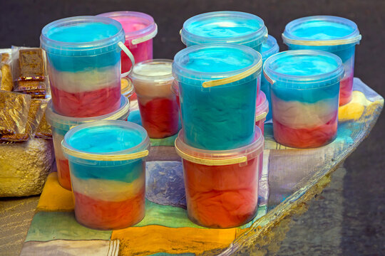Multi colored cotton candy floss material packaged in clear plastic buckets