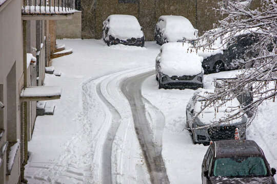Cars parked outside in urban city street during winter covered by snow