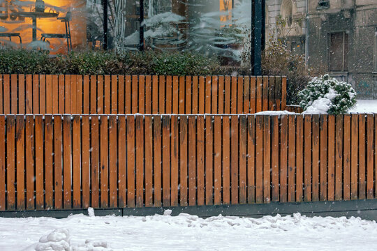 Double wooden fence outside in urban city street  under snow during winter season 