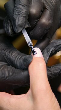 A woman's hand during a manicure. A woman getting a manicure. A manicurist is doing a client's nails at a nail salon. Manicure services - Vertical video