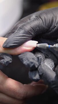A woman's hand during a manicure. A woman getting a manicure. A manicurist is doing a client's nails at a nail salon. Manicure services - Vertical video