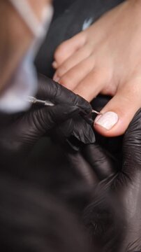 A woman's feet during a pedicure. Woman getting pedicure in beauty salon, closeup. A pedicurist working at a beauty salon. Beauty salon concept: pedicures - Vertical video