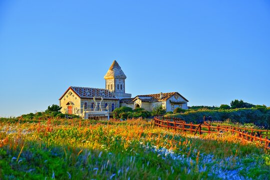 White cottage stands at Seopjikoji during magic hour on Jeju Island, South Korea with lush fields surrounding it