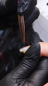A woman's hand during a manicure. A woman getting a manicure. A manicurist is doing a client's nails at a nail salon. Manicure services - Vertical video