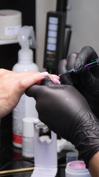 A woman's hand during a manicure. A woman getting a manicure. A manicurist is doing a client's nails at a nail salon. Beauty salon concept: manicures, pedicures - Vertical video 