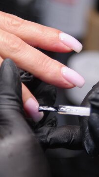 A woman's hand during a manicure. A woman getting a manicure. A manicurist is doing a client's nails at a nail salon. Beauty salon concept: manicures, pedicures - Vertical video 
