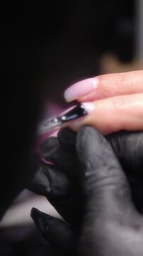 A woman's hand during a manicure. A woman getting a manicure. A manicurist is doing a client's nails at a nail salon. Beauty salon concept: manicures, pedicures - Vertical video 