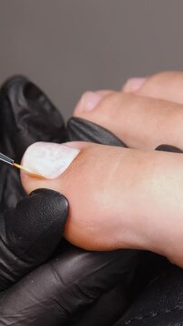 A woman's feet during a pedicure. Woman getting pedicure in beauty salon, closeup. A pedicurist working at a beauty salon. Beauty salon concept: pedicures - Vertical video