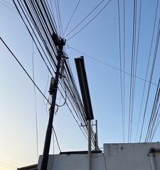 Obraz premium Utility pole with tangled power lines against a blue sky