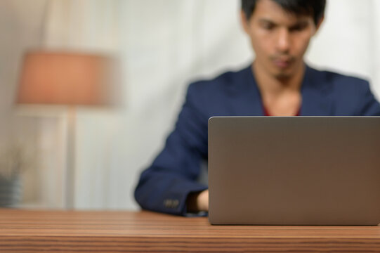 Young Man Working on Laptop at Desk in Modern Room with Warm Lighting
