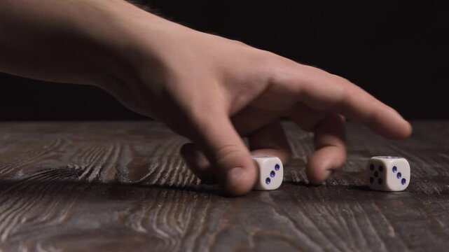Close-up of a hand collecting dice from a wooden table
