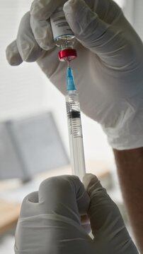 Vertical shot of healthcare professional hands in sterile gloves drawing vaccine from vial into syringe. Clip is ideal for medical training videos and public health vaccination campaigns