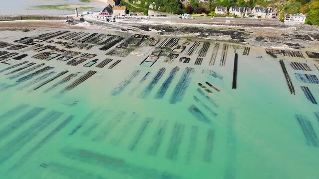 Drone aerial view of oyster farm beds and shellfish cultivation area in Cancale, France, during low tide on the coast