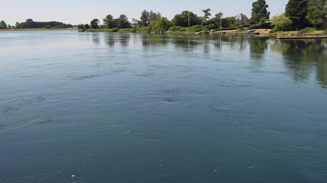 Swirling river current and water vortices near green lush shoreline