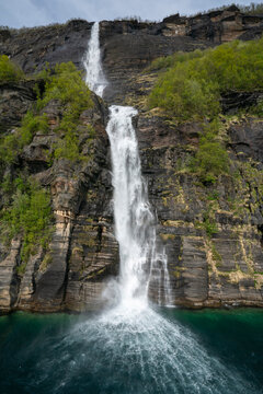 Waterfall cascades down rocky cliff in Melfjord near Melfjordbotn in Nordland, Norway