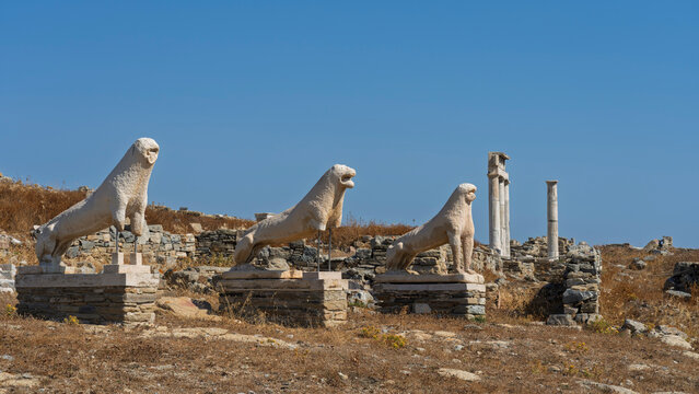 Sculptures of lions stand on the Terrace of the Lions in the Delos archaeological site in Greece under a clear blue sky
