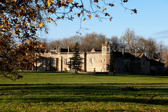 Visit to Lacock Abbey on a clear day with bright blue sky and greenery surrounding the historic structure in Wiltshire