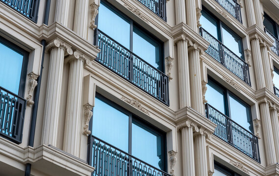 Architectural design of a building facade with columns and balconies in a city setting during daytime