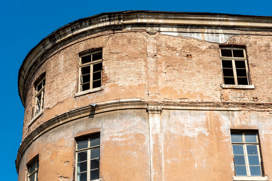 Old building with damaged walls and empty windows under clear blue sky in daytime