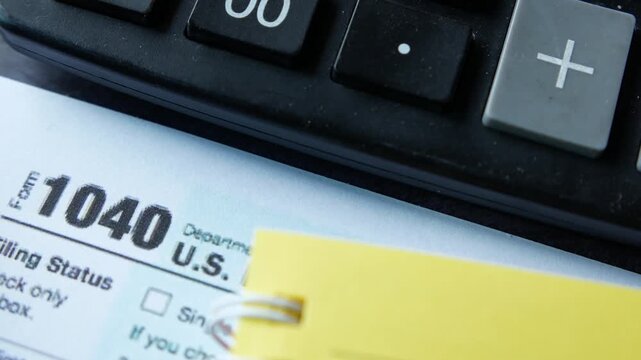 Close up on tax form 1040 with calculator pencils and coins