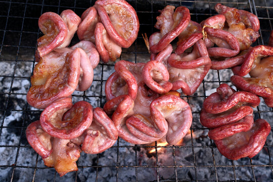 Pork offal being grilled on barbecue in a street food scene in Luang Prabang, Laos during evening hours