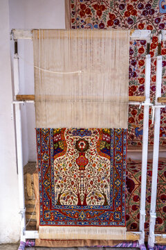 Artisans weave traditional carpet on loom in historical Itchan Kala in Khiva, Uzbekistan, showcasing intricate patterns and craftsmanship