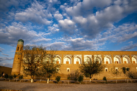 Former Muhammad Mahram madrasa stands in Khiva under a dynamic sky filled with clouds at sunset