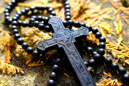 Dark beaded rosary resting among autumn leaves with crucifix, representing hope and devotion in fall season in France