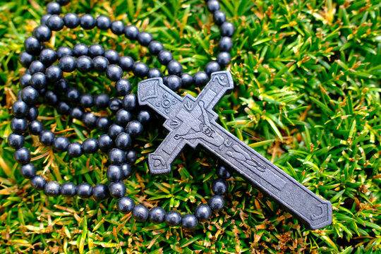 Dark ebony rosary with carved crucifix on yellow heather and green shrubbery in France