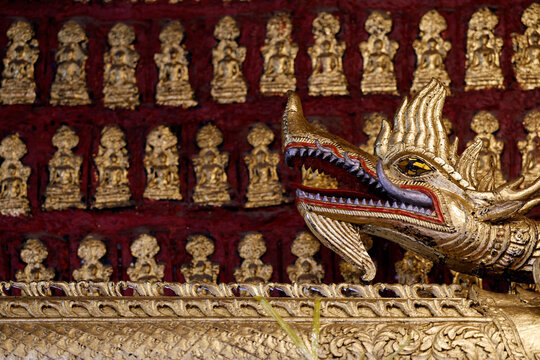 Golden dragon sculpture at Wat May Souvannapoumaram temple in Luang Prabang showcases traditional Buddhist artistry
