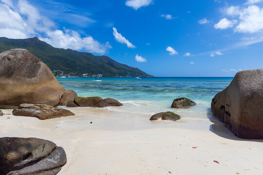 Beautiful white sandy beach with crystal-clear waters, rocky formations, and a serene atmosphere inviting relaxation and exploration. Beau Vallon beach landscape, Seychelles
