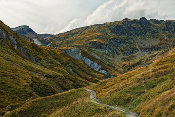 Fototapeta premium Col des Fours, France - 2025: Winding Dirt Path Through Rugged Mountain Val...