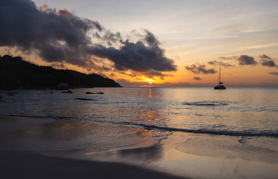 Peaceful scene featuring a tranquil beach at sunset, highlighting the warm hues of skies and clouds, creating a calming and relaxing atmosphere by the ocean. Seychelles