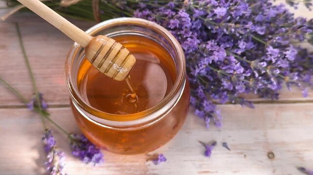 Dipping honey dripper in lavender honey jar