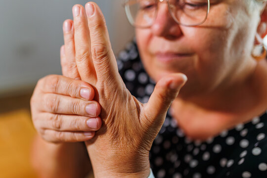 Senior woman rubbing her hands together examining aging skin.