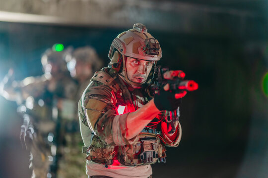 Military tactical operator aims rifle with weapon light in dark abandoned building interior