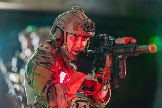 Military tactical operator aims rifle with weapon light in dark abandoned building interior