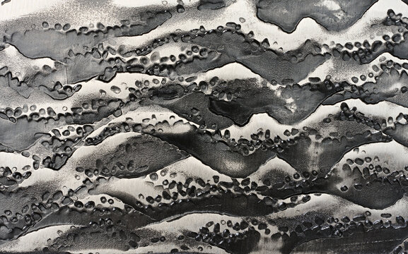 Close-up of the forged steel texture on a knife blade with a raised dark pattern.