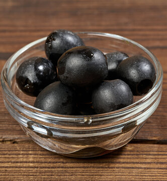 Pitted olives in a glass bowl on a wooden table