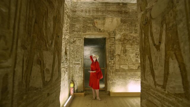 Woman in a red dress exploring the temple in Abu Simbel, Egypt.