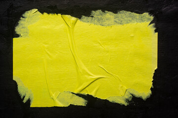 Fototapeta na wymiar A yellow poster with folds on a black background, close-up
