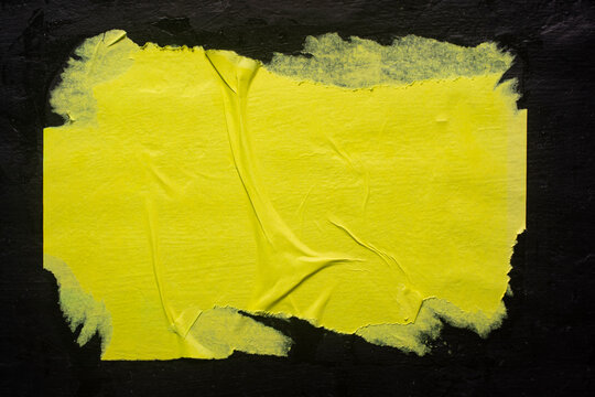 A yellow poster with folds on a black background, close-up